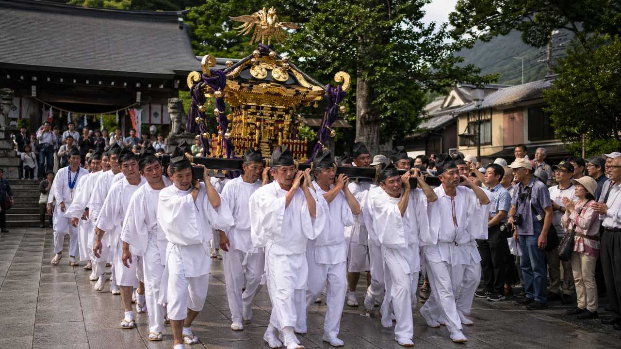 伝統的な神輿渡御をイメージした祭礼風景、神社の境内から町へ進む神輿、参拝者が見守る様子