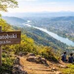 岐阜県の低山「鳩吹山」を初心者向け登山ブログのアイキャッチとして表現する、春のやわらかな朝の光、山頂から木曽川と広がる町並みを見下ろす開放感のある構図