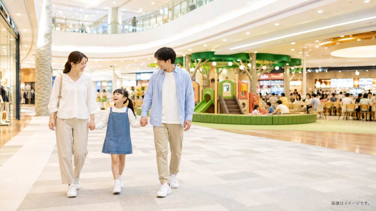 岐阜県の大型ショッピングモールをイメージした明るい屋内空間で、親子が楽しそうに歩き、背景にキッズスペースや遊具、フードコートの雰囲気が自然に見える実写風写真。