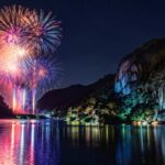 恵那峡の静かな湖面に色鮮やかな花火が反射し、渓谷のシルエットが夜空に浮かぶ実写風のブログ用アイキャッチ画像